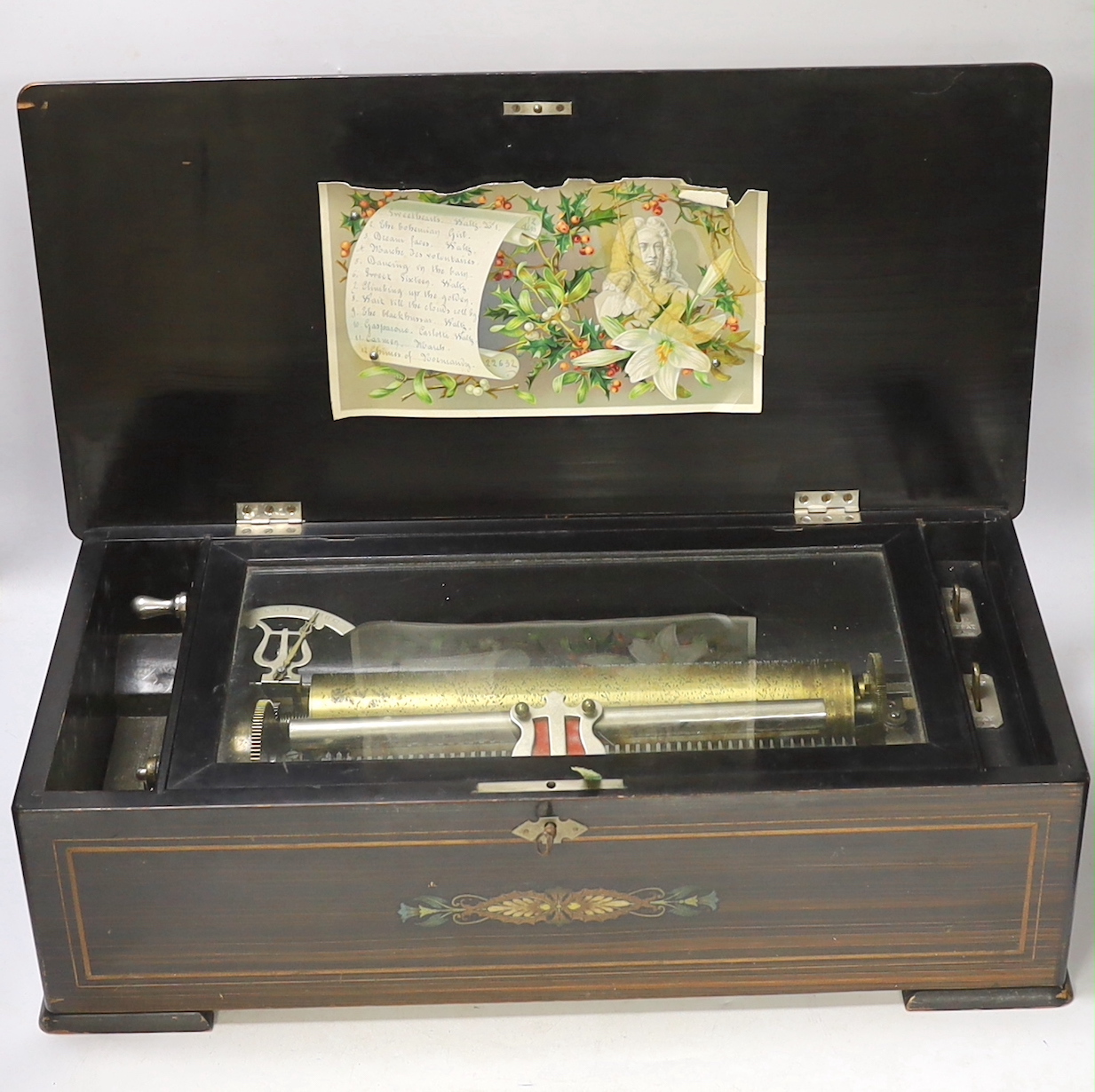 A late 19th century Swiss inlaid rosewood cased musical box, single cylinder with a 52 note comb playing twelve airs, tune indicator below glass dust cover, with tune list on underside of lid, 51 x 16 x 25cm